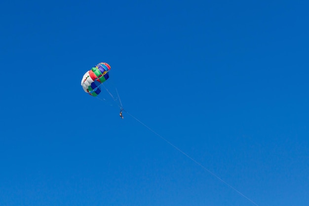 Skydiver flying with a colorful parachute by speed boat on sea