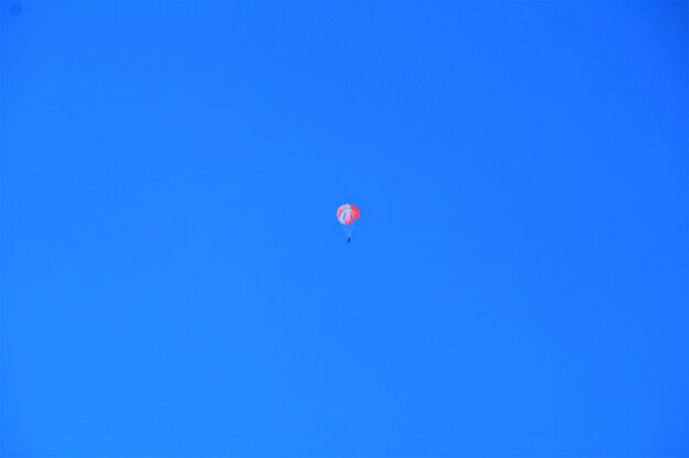 Skydiver with colorful dome in the blue sky