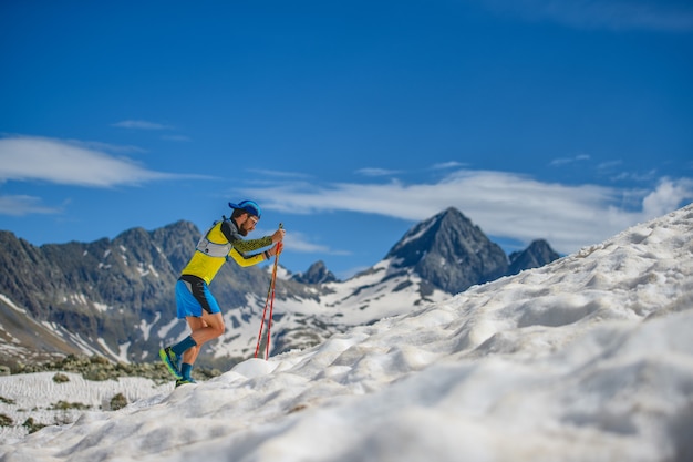 Skyrunning opleiding met stokken op de sneeuw bergopwaarts