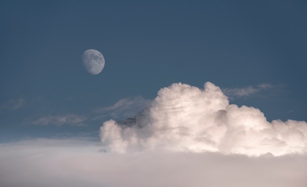 Skyscape、ふわふわの雲の上の青い空にほぼ満月