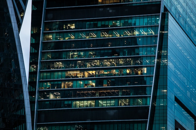 Skyscraper building with office windows, evening view with turned on lights