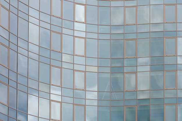 Superficie di vetro dello specchio del grattacielo che riflette cielo nuvoloso, superficie curvy