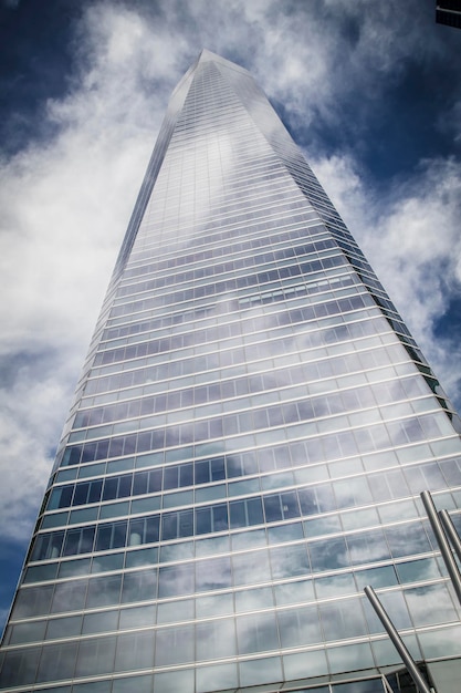 skyscraper with glass facade and clouds reflected in windows