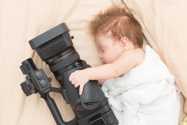 Slaap pasgeboren meisje dat een videocamera houdt.