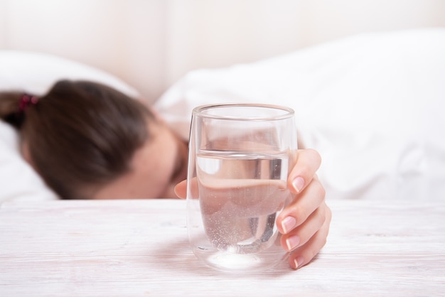 Slaapvrouw die hand overgaan aan glas water