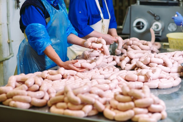 Slagers die worsten verwerken bij vleesfabriek.