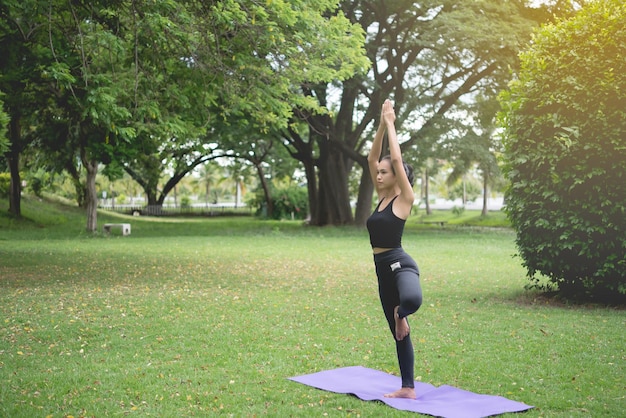 Slank meisje speelt yoga op het grasveld in het parkrelax in nutureAziatische meisjes houden van gezondheid door yoga te beoefenen