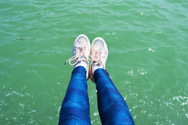 slanke benen in kleurrijke schoenen tegen de achtergrond van water