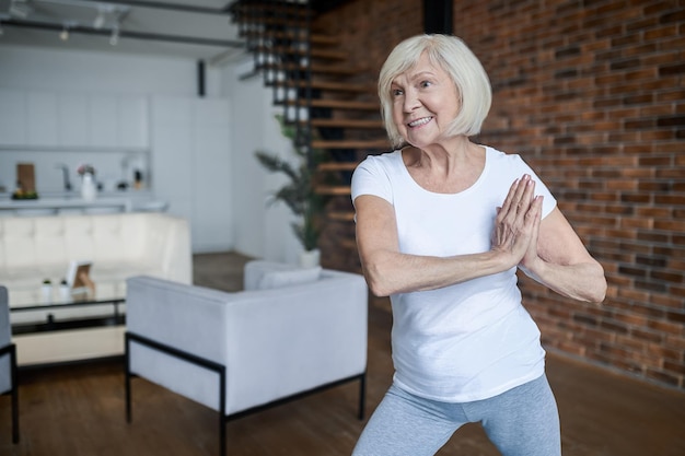 Slanke ouder wordende vrouw die thuis yoga doet