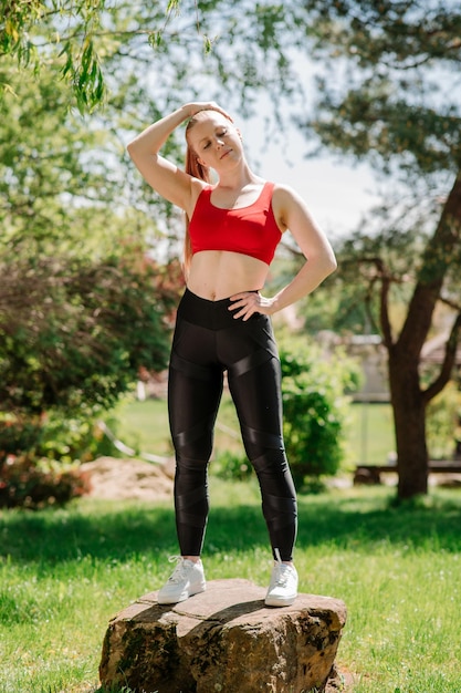 Slanke sportieve jonge vrouw in sportkleding poseren of rusten buiten in het park