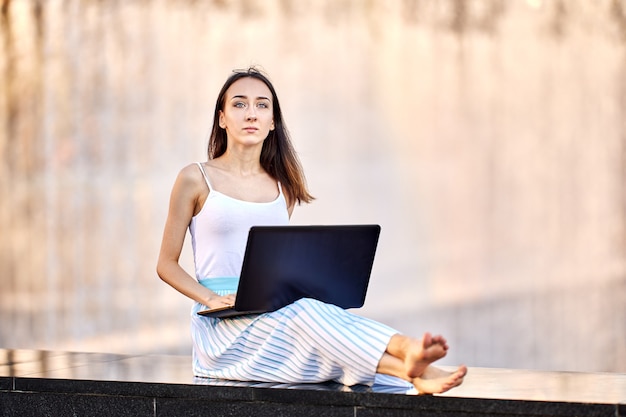 Slanke vrouw heeft e-learning met laptop buitenshuis