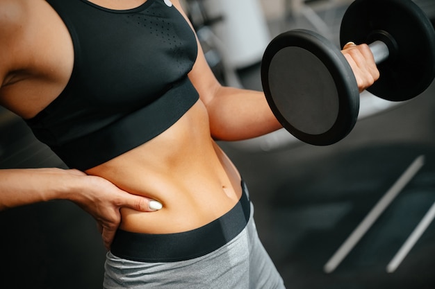 Slanke vrouw houdt zich bezig met fitness tillen dumbbells oefeningen voor spieren van armen concept van sport...