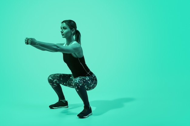 Slanke vrouw hurkt tijdens training