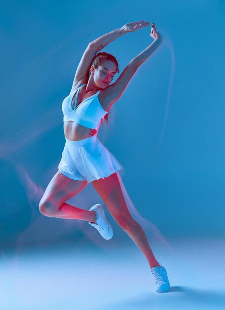 Slanke vrouw in activewear dansen met handen omhoog fitness dieet huid en lichaamsverzorging motion blur effect