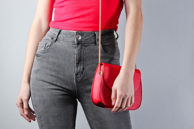 Slanke vrouw in jeans en t-shirt met rode tas.