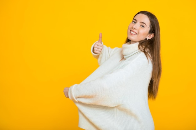 Slanke vrouw in oversized trui op gele achtergrond Gewichtsverlies