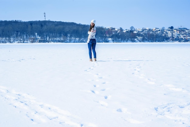 Slanke vrouw in spijkerbroek en een trui Achteraanzicht Witte muts en handschoenen Winterrust