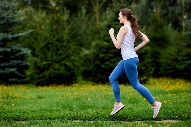 Slanke vrouw in sportkleding rent in stadstuin