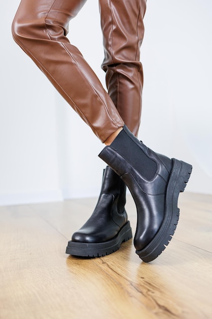 Slanke vrouwelijke benen in zwarte leren chelsea-laarzen Lente-herfst dameslaarzen Vrouwelijke benen in leren bruine broek