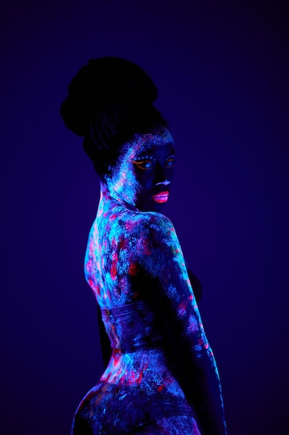 Slanke zwarte vrouw met luminescentie, fluorescentie, body art geïsoleerd op dark