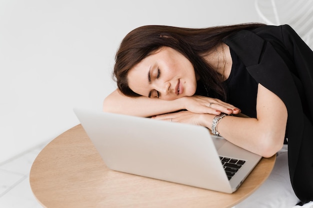 Slapend meisje met laptop op tafel op witte achtergrond Vermoeide jonge vrouw heeft een pauze op het werk en slaapt en ontspant op laptop op de werkplek vanwege overwerk