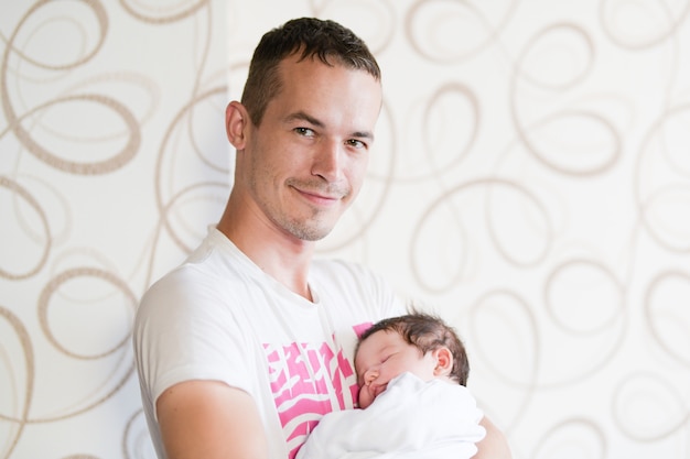 Slapende baby in de armen van zijn vader. portret van een jonge vader die zijn pasgeboren babyzoon thuis houdt.