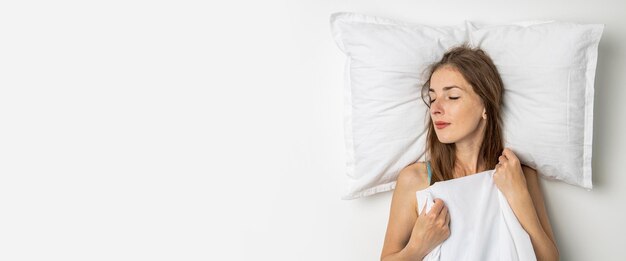 Slapende jonge vrouw liggend in een wit bed Bovenaanzicht plat lag Banner