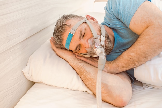 slapende man met chronische ademhalingsproblemen met cpap-machine in bed