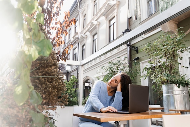 Slapende meisje met laptop op tafel buiten in café Moe jonge vrouw heeft een pauze op het werk en slapen en ontspannen op laptop op werkplek vanwege overwerk