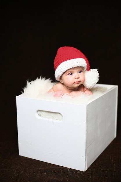 Slapende pasgeboren babyjongen van twee weken oud met een gehaakte kerstmuts met sneeuwpop knuffel