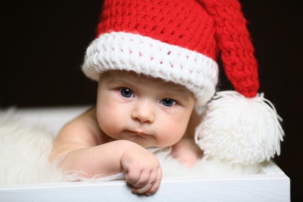 Slapende pasgeboren babyjongen van twee weken oud met een gehaakte kerstmuts met sneeuwpop knuffel