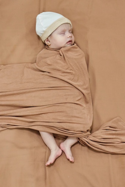Slapende pasgeboren babymeisje gewikkeld in een bruine deken