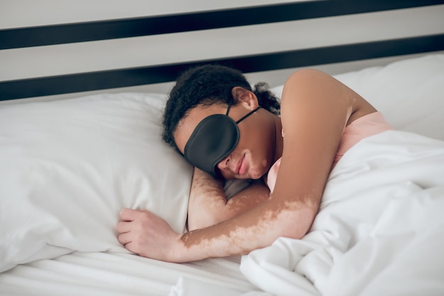 Slapende vrouw. Jonge vrouw met een masker om in bed te slapen