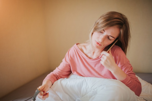 Slaperige jonge vrouw wakker met alarm. Ze heeft zich verslapen om te werken