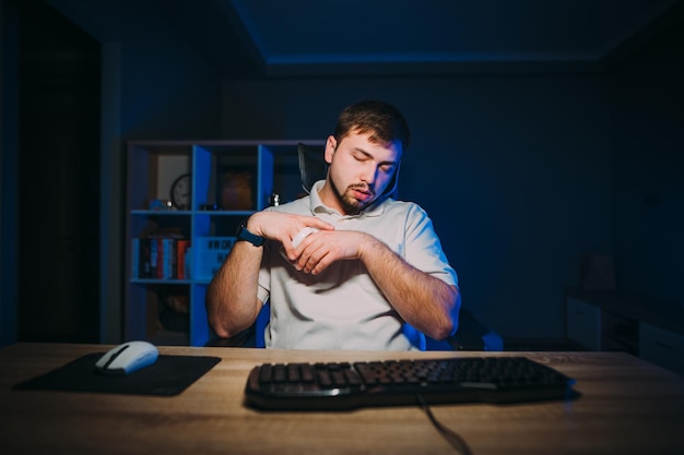 Slaperige man slaapt aan het computerbureau tijdens nachtwerk