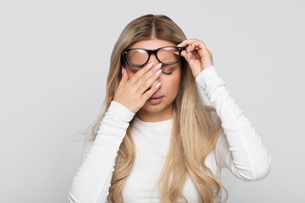 Slaperige vrouw in glazen ogen wrijven voelt zich moe