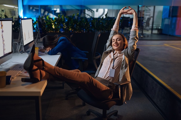 Slaperige vrouwen werken op computers in het nachtkantoor