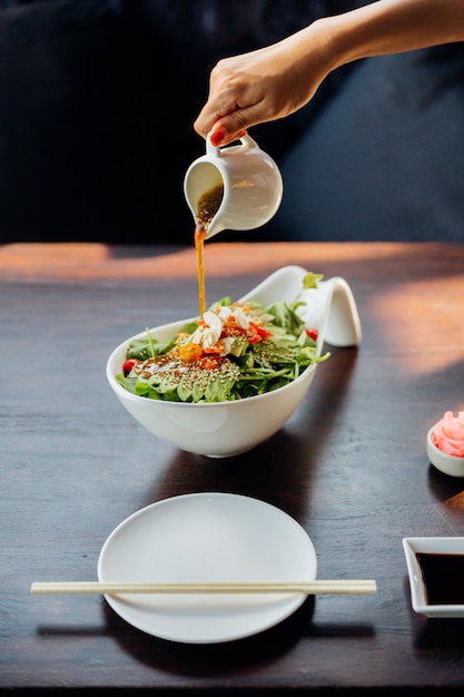 Slasamasaus van de hand gietende op Japanse salade.