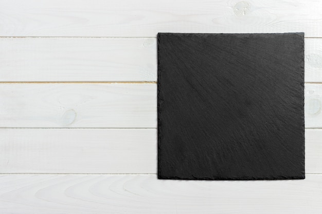 Slate board on wooden background, space for writing text