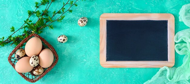 Slate plate, eggs in a basket, green branches on a bright background. 