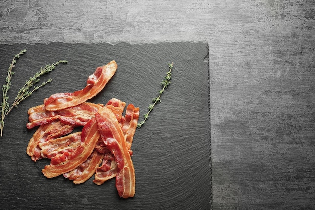 Photo slate plate with cooked bacon rashers on table