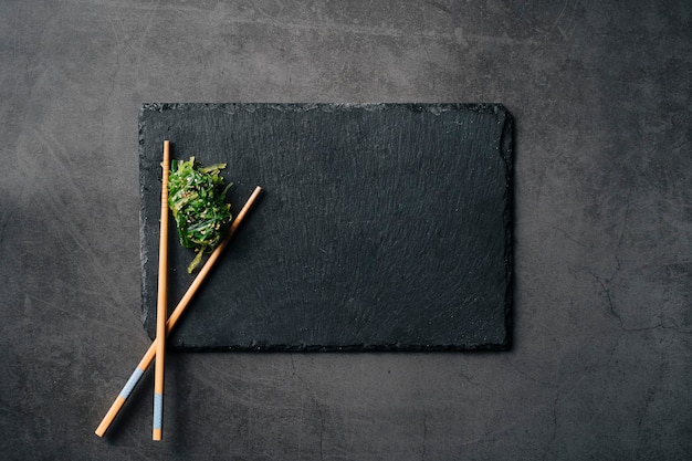 Slate plate with Japanese seaweed. Dark background. Top View. Copy Space.