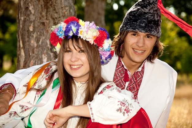 Ragazza slava con corona e giovane cosacco in natura.