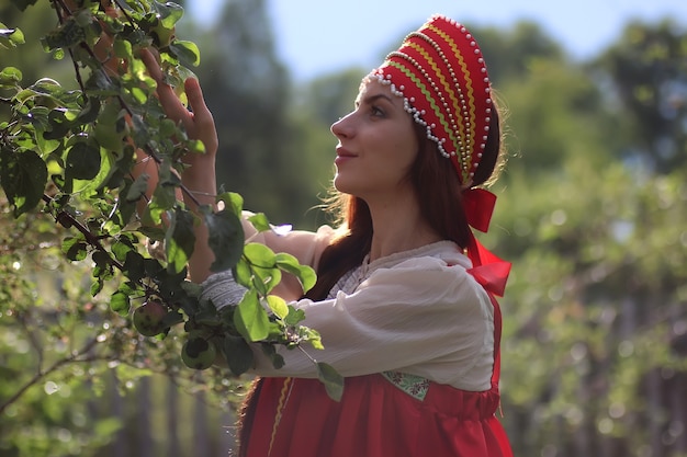 Славянин в традиционной одежде собирает урожай яблок