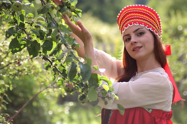 전통 의상을 입은 슬라브는 사과 수확을 수집합니다.