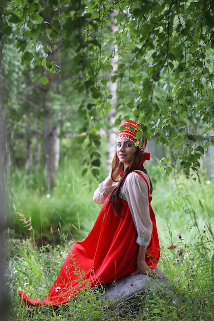 Славянин в традиционной одежде сидит на природе
