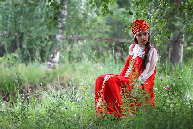 Slav in traditional dress is sitting in nature