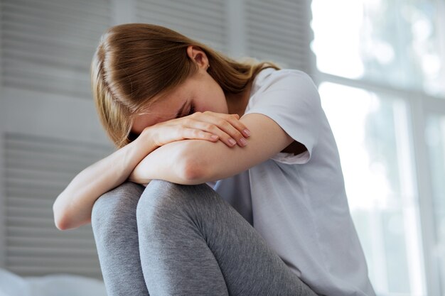 Slecht nieuws. Arme blonde vrouw die zit te huilen en haar hoofd naar beneden heeft