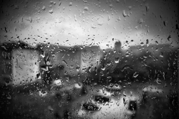 Slecht weer in de stad Gebouwen huizen auto's buiten het raam Bewolking stapelwolken Meteorologie en weersvoorspelling Regendruppels rennen door het glas Storm en storm en wind op straat in de stad