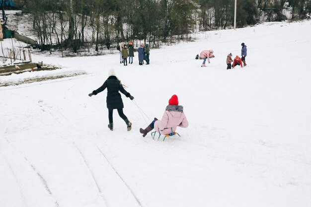 Sledding in winter group of happy children walking with sled in winter